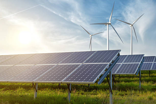Stock photo of wind turbines and solar panels in a grass field.