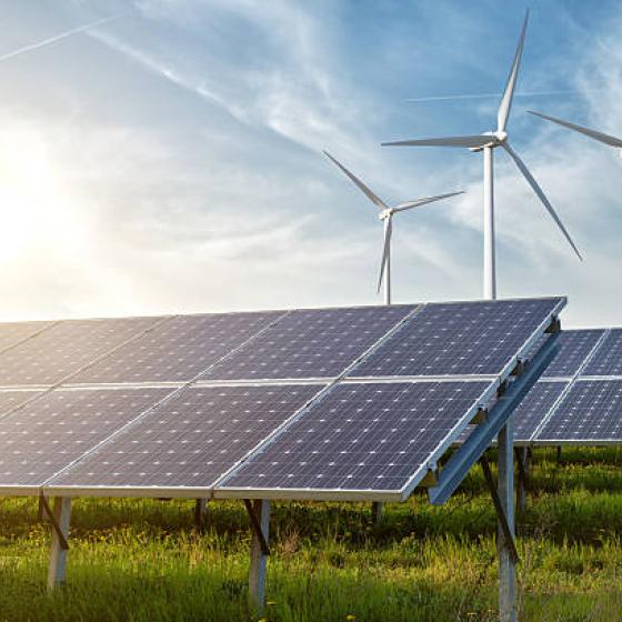 Stock photo of wind turbines and solar panels in a grass field.