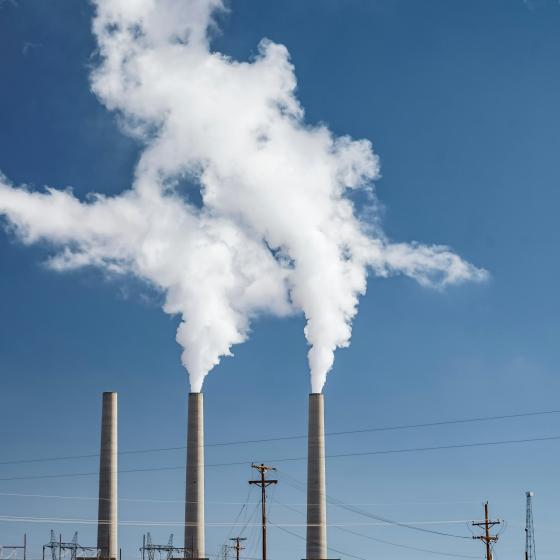 Gray concrete factory chimney releasing smoke