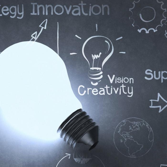 light bulb in front of a classroom board with the words strategy innovation, vision creativity, support and solution